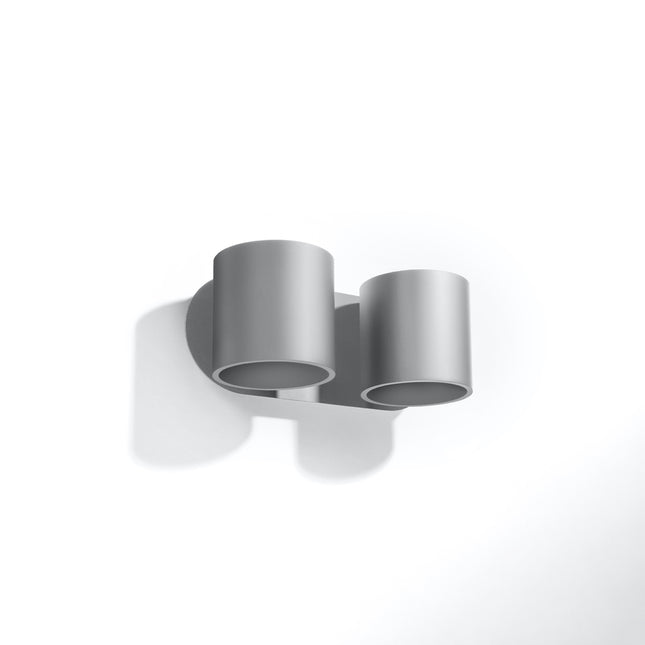 Applique murale à deux cylindres en aluminium gris clair mat sur base ovale, ouvertures orientées vers le bas.