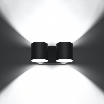 Applique cylindrique double noire allumée de face, faisceaux lumineux projetés vers le haut et vers le bas.