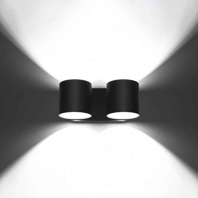 Applique cylindrique double noire allumée de face, faisceaux lumineux projetés vers le haut et vers le bas.