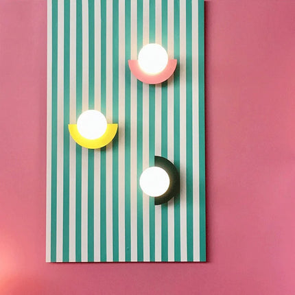 Trio d'appliques murales LED demi-cercle colorées, disposées sur un fond décoratif rayé