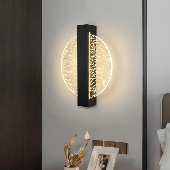 Applique murale disque lumineuse installée en tête de lit dans une chambre au mur clair et bois foncé