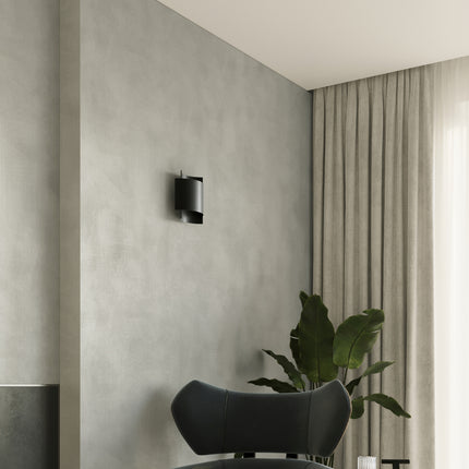 Applique murale double arc acier noir en ambiance, salon avec fauteuil et plante