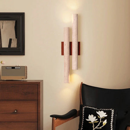 Applique murale double en travertin diffusant une lumière ambrée près d'un fauteuil en cuir noir