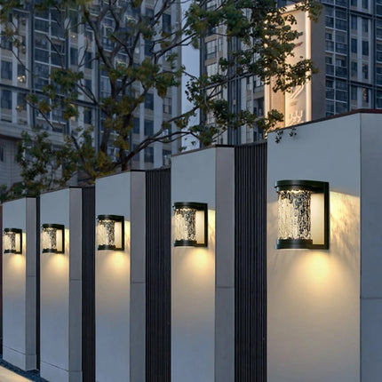 Appliques murales extérieures effet cristal alignées sur des façades éclairées à la tombée de la nuit