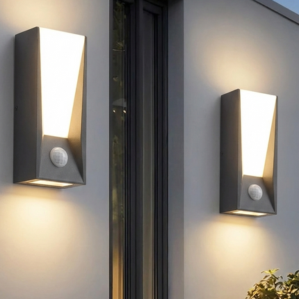 Deux appliques murales extérieures LED anthracite avec détecteur diffusant une lumière chaude sur un mur de terrasse