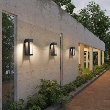 Alignement d'appliques extérieures noires le long d'un mur bordant une allée de jardin