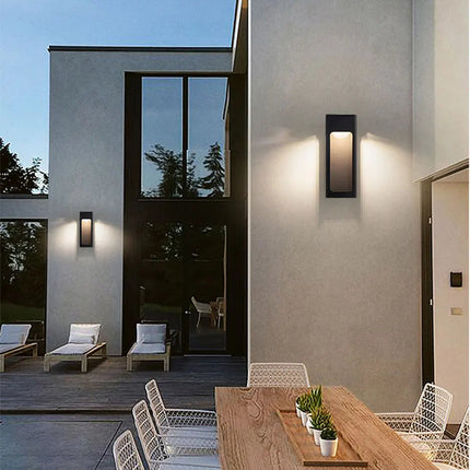 Deux appliques extérieures noires allumées sur un mur de maison contemporaine au crépuscule