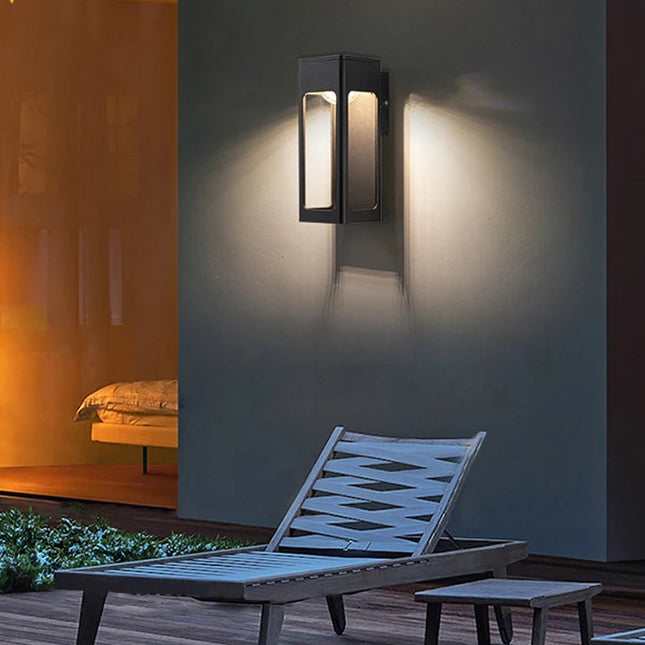 Applique extérieure noire allumée en blanc chaud sur un mur de terrasse la nuit