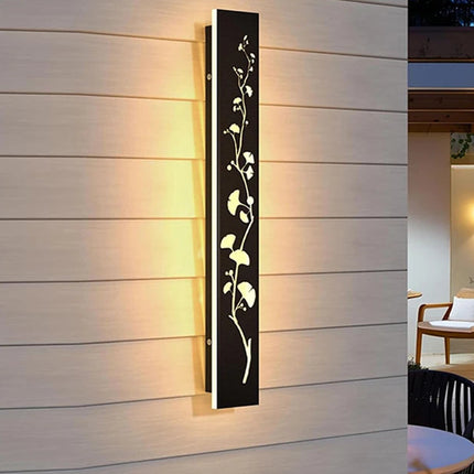 Applique murale extérieure noire à motif feuillage ajouré et LED allumée sur une façade en bois