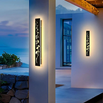 Appliques murales extérieures noires à motif feuillage ajouré éclairant une terrasse face à la mer