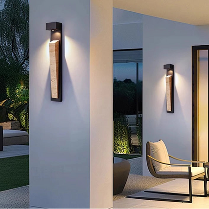 Applique murale extérieure en pierre naturelle et aluminium noir installée sur une façade de jardin