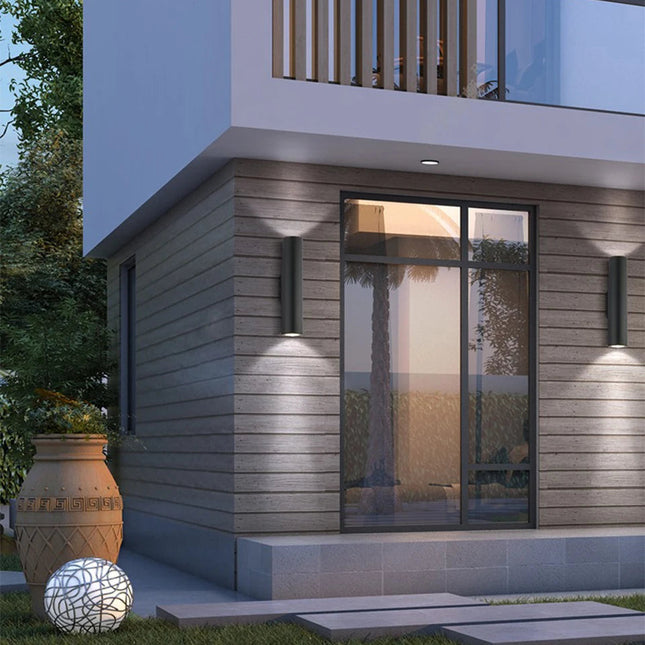 Appliques murales extérieures tube LED noires sur une façade de maison contemporaine la nuit