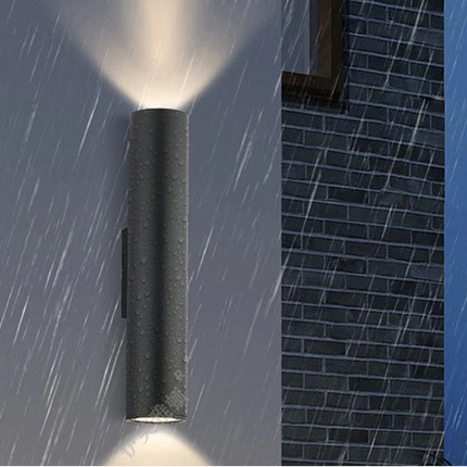 Applique murale extérieure tube LED noire sous la pluie, étanchéité IP67 sur un mur en brique