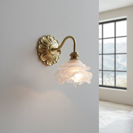 Applique murale fleur en laiton doré allumée près d'une fenêtre, lumière tamisée sur mur gris clair
