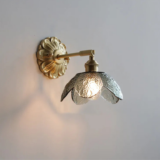 Applique murale fleur en verre texturé fumé et laiton doré, bras orientable, allumée sur un mur clair