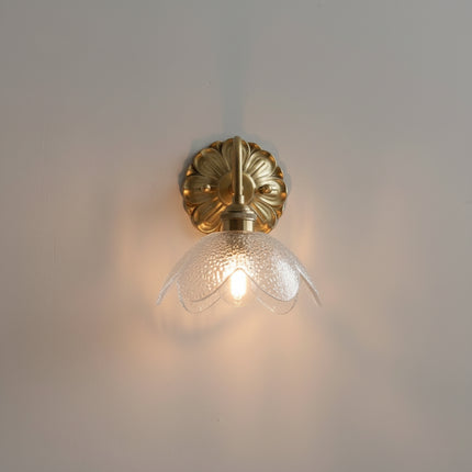 Applique murale fleur en verre transparent allumée, vue de face avec pétales clairs et lumière chaude