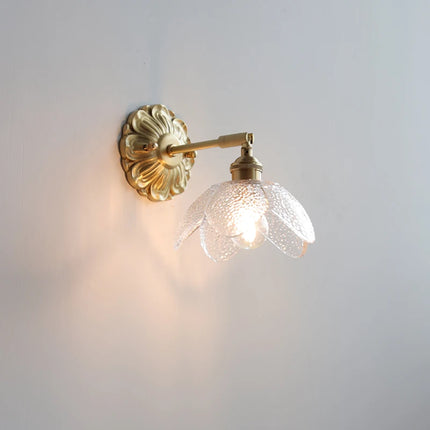 Applique murale fleur en verre transparent texturé et laiton doré, ampoule allumée dans un intérieur doux