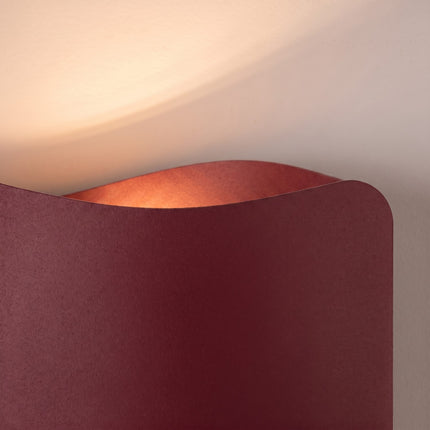 Applique murale Flux Lumineux 30 en acier bordeaux sur fond coloré, vue de trois quarts