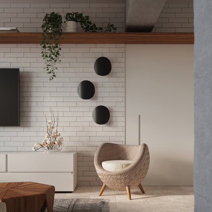 Trois appliques galet noir mat alignees sur un mur de briques claires dans un salon japandi