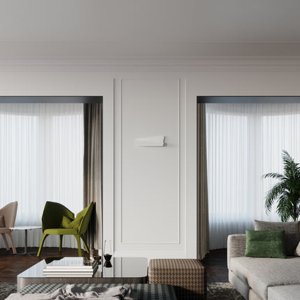 Applique murale ajourée blanche sur un mur de salon contemporain avec fauteuil vert et plante