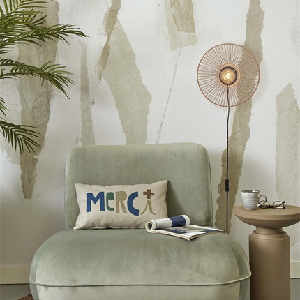 Applique murale ronde en bambou naturel allumée au-dessus d'un fauteuil vert dans un salon cosy