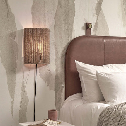 Applique murale Iguazu en jute tressé au-dessus d'une tête de lit en cuir, lumière tamisée
