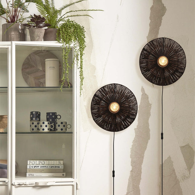 Two lit black jute Iguazu wall lights installed on either side of a white dresser