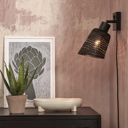 Applique murale Java orientable en bambou noir, allumée au-dessus d'une commode noire dans une chambre