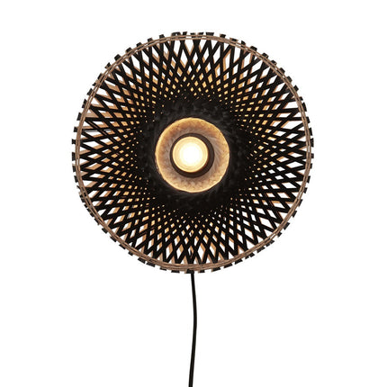 Applique murale Kalimantan en bambou tressé noir sur fond blanc, câble textile noir et ampoule allumée
