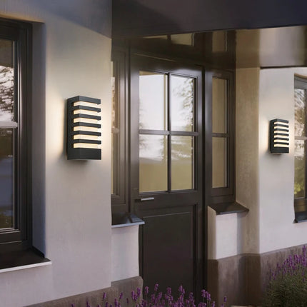Deux appliques murales LED en aluminium anthracite allumées de part et d'autre d'une porte d'entrée