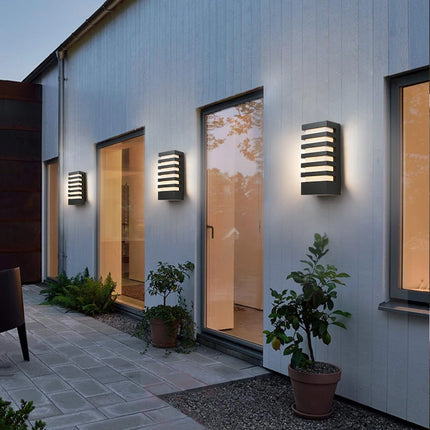 Trois appliques murales LED anthracite sur une façade extérieure au-dessus d'un jardin