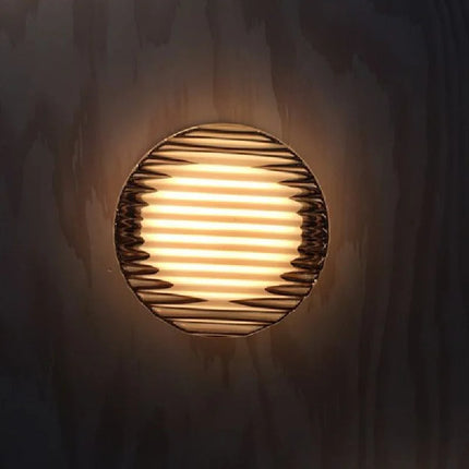 Applique boule acrylique ondulée diffusant une lumière chaude sur un mur en bois