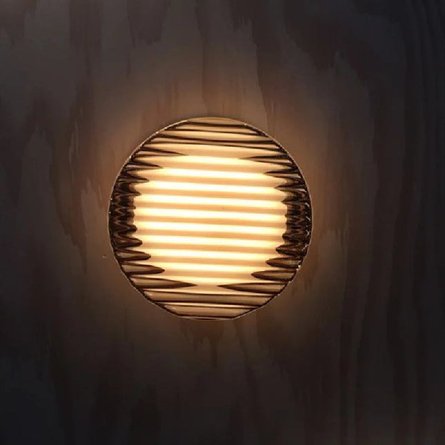 Applique boule acrylique ondulée diffusant une lumière chaude sur un mur en bois