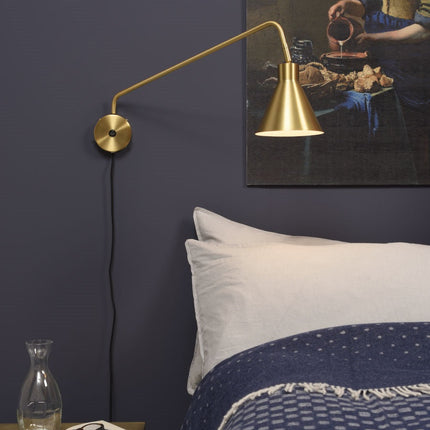 Applique murale Lyon dorée installée en tête de lit dans une chambre aux tons bleu nuit
