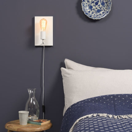 Applique murale Madrid blanche allumée au-dessus d'une table de chevet dans une chambre bleu nuit
