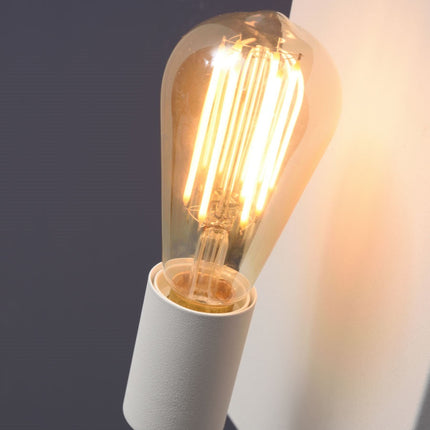 Gros plan sur l'ampoule à filament vissée sur le culot blanc de l'applique murale Madrid