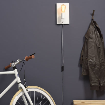 Applique murale Madrid rectangulaire en fer blanc allumée au-dessus d'un vélo dans une entrée sombre