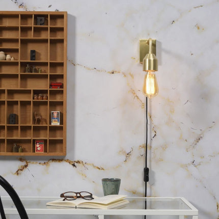 Applique murale Madrid en fer doré au-dessus d'un bureau, ampoule filament allumée sur mur effet marbre