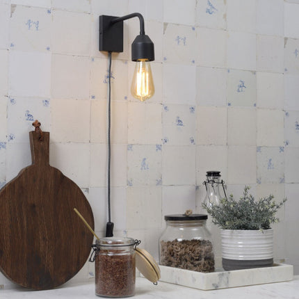 Applique murale noire au design minimaliste installée dans une cuisine au carrelage bleu et blanc traditionnel