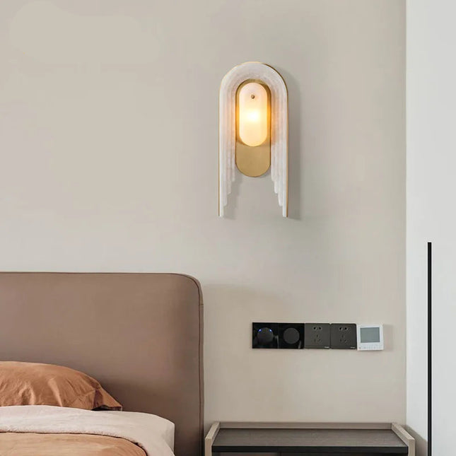 Applique murale en marbre et cuivre doré installée au-dessus d'une tête de lit dans une chambre feutrée