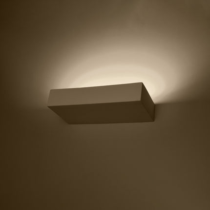 Applique murale céramique blanche allumée, halo de lumière chaude indirecte sur le mur