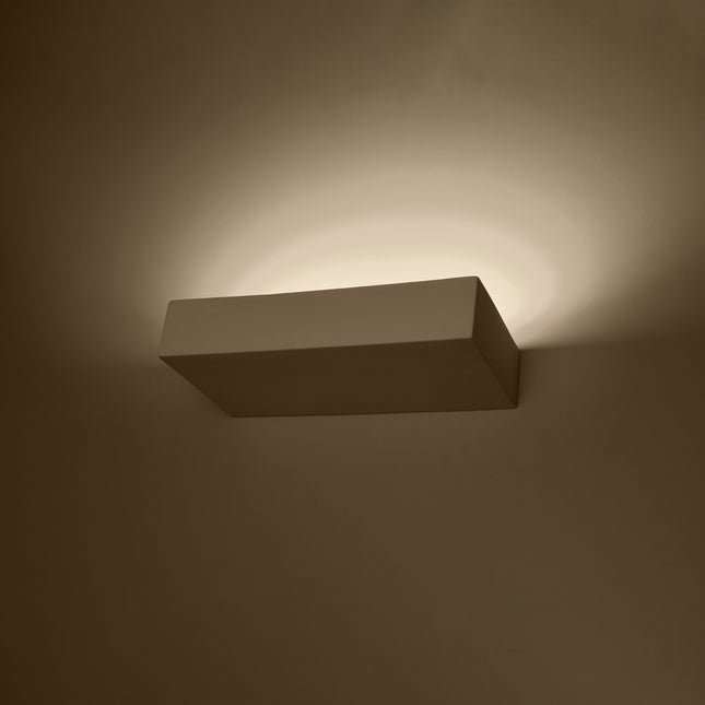 Applique murale céramique blanche allumée, halo de lumière chaude indirecte sur le mur