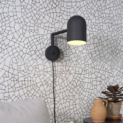 Applique murale Marseille en fer noir, bras orienté, sur mur à motifs graphiques