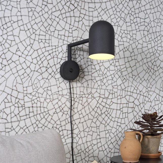 Applique murale Marseille en fer noir, bras orienté, sur mur à motifs graphiques
