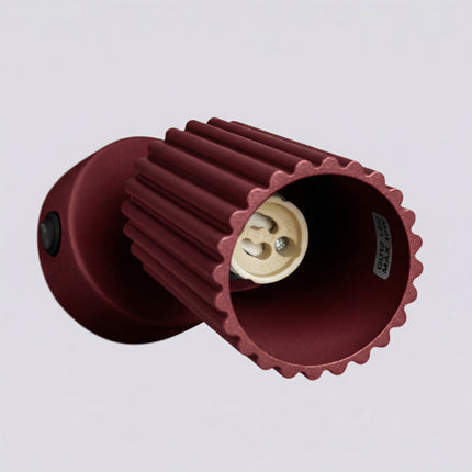 Applique Murale Orientable Oslo avec Interrupteur en Aluminium Cannelé Bordeaux, vue sur fond coloré