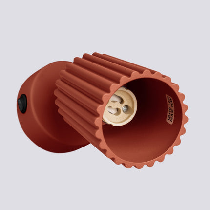 Applique murale orientable Oslo avec interrupteur rouge ocre, vue sur fond coloré