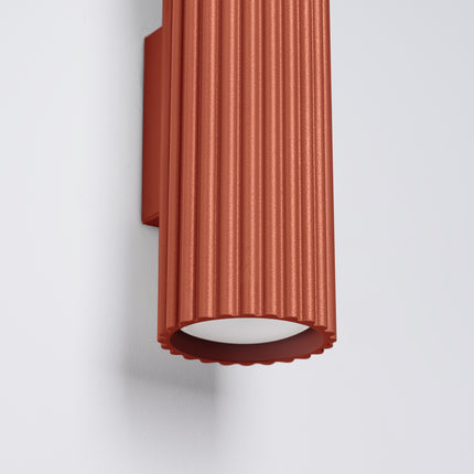 Gros plan sur l'ouverture inférieure cannelée de l'applique Oslo 30 rouge ocre, lumière GU10 diffusée
