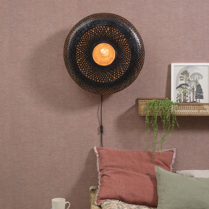 Applique murale Palawan en bambou tressé noir et naturel diffusant une lumière chaude dans une chambre