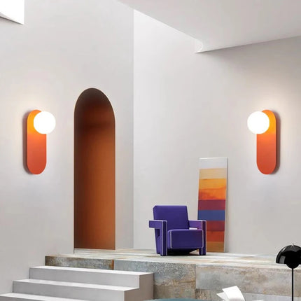 Deux appliques murales pilule orange encadrant une niche dans un salon design
