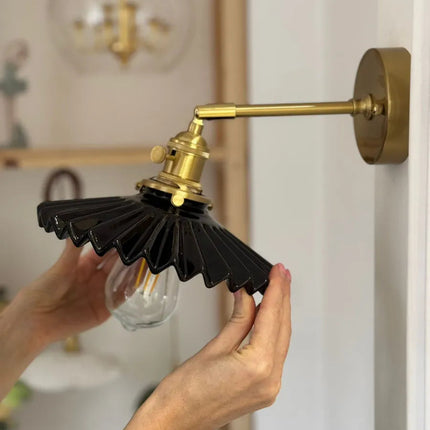Applique murale plissée noire et laiton installée dans un intérieur nordique, bras orienté vers le bas